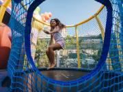 Bambina che si diverte su un trampolino circondato da una rete di sicurezza.