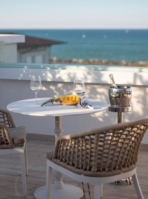 Tavolo con vista mare, due bicchieri di vino e un secchiello per il ghiaccio.