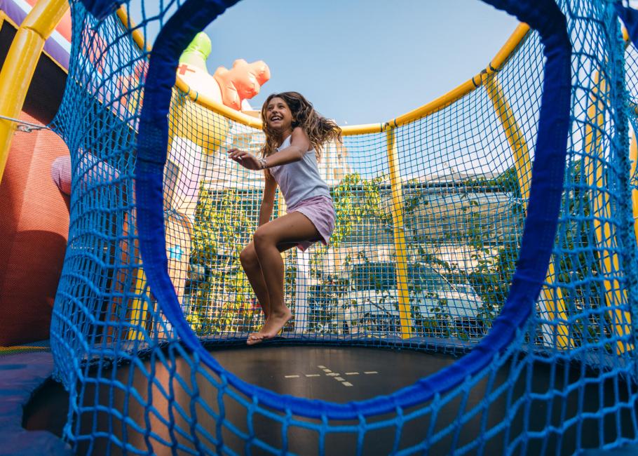 Bambina che si diverte su un trampolino circondato da una rete di sicurezza.