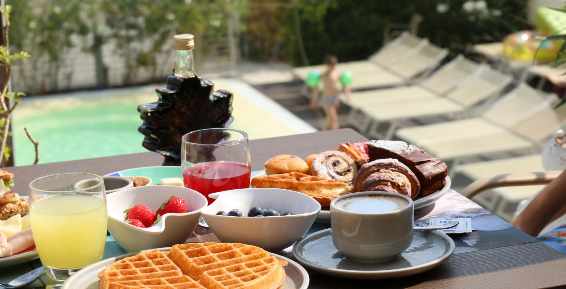 Colazione a bordo piscina con waffle, frutta, dolci e bevande.