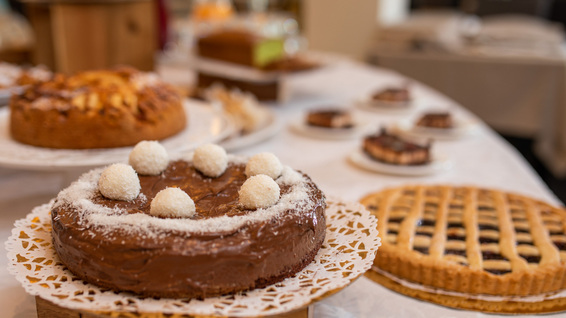 Tavola imbandita con dolci vari, tra cui torte al cioccolato e crostate.