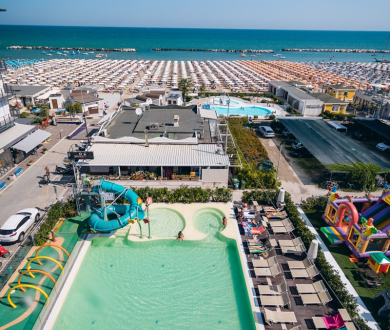 Persone si rilassano in una piscina con scivoli e giochi d'acqua.