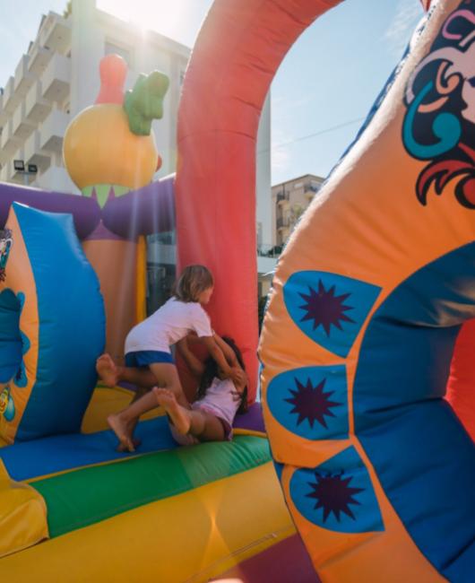 Bambini giocano su un castello gonfiabile colorato in una giornata di sole.