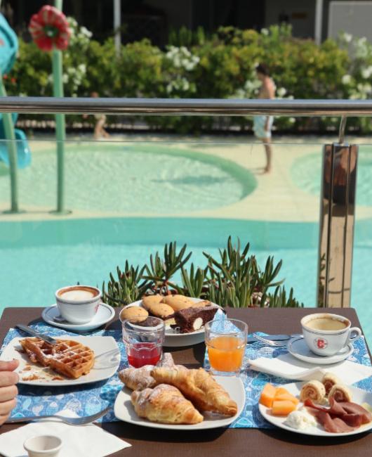 Colazione all'aperto con dolci e caffè, vista sulla piscina.