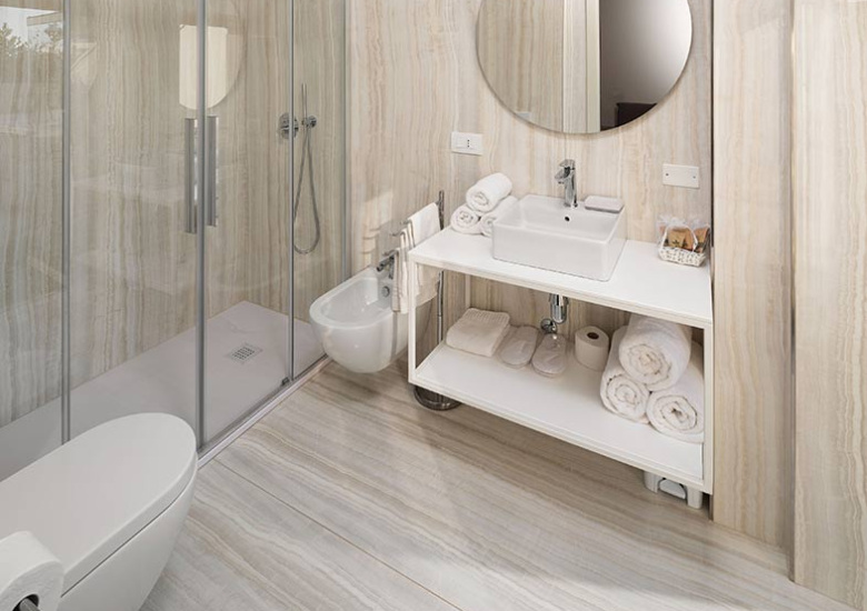 Bagno moderno con doccia, lavabo, bidet e decorazioni in tonalità neutre.