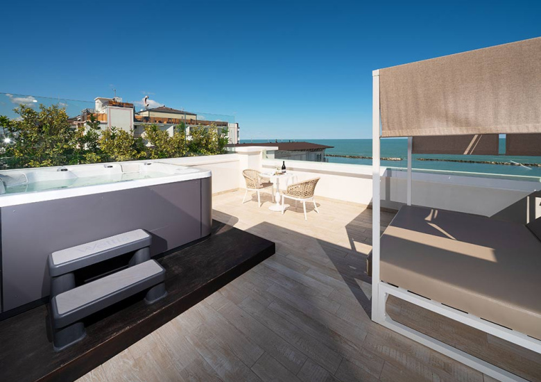 Terrazza con jacuzzi, lettino e vista mare, perfetta per relax e comfort.