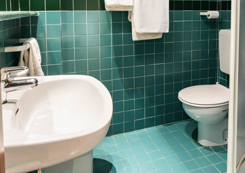 Bagno con piastrelle verdi, lavabo, WC e doccia.