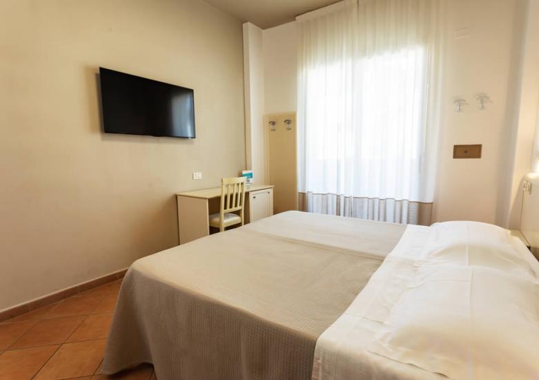 Camera d'albergo semplice con letto matrimoniale e TV a parete.