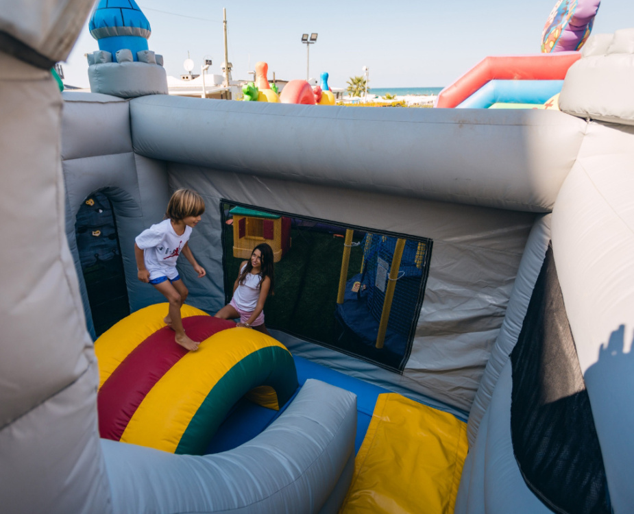 Bambini giocano su un castello gonfiabile colorato in una giornata di sole al mare.